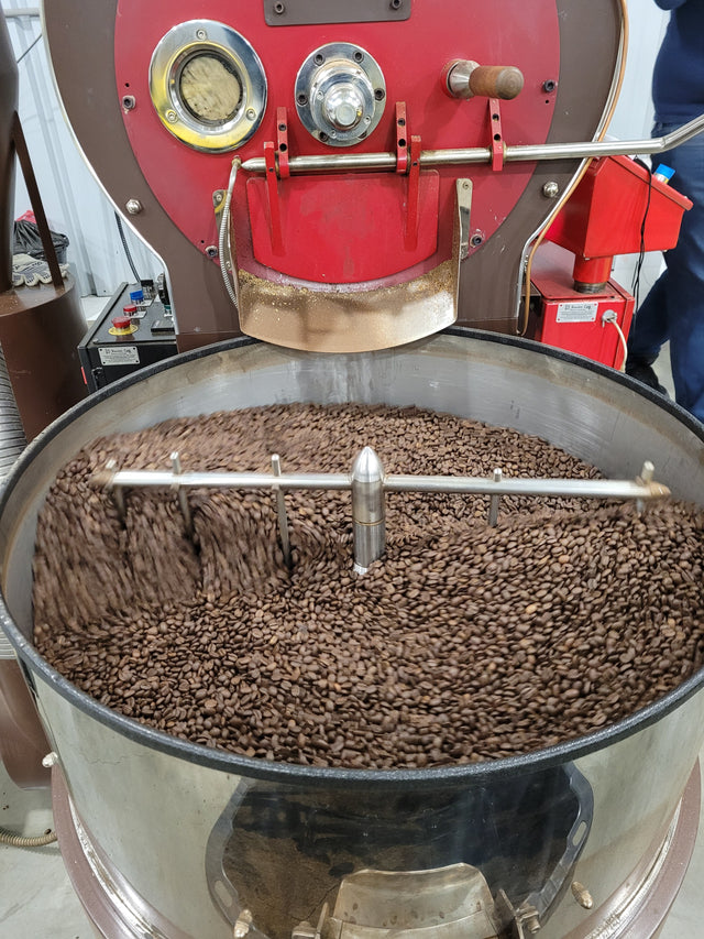 Front view of the coffee roaster with beans being stirred in the cooling tray