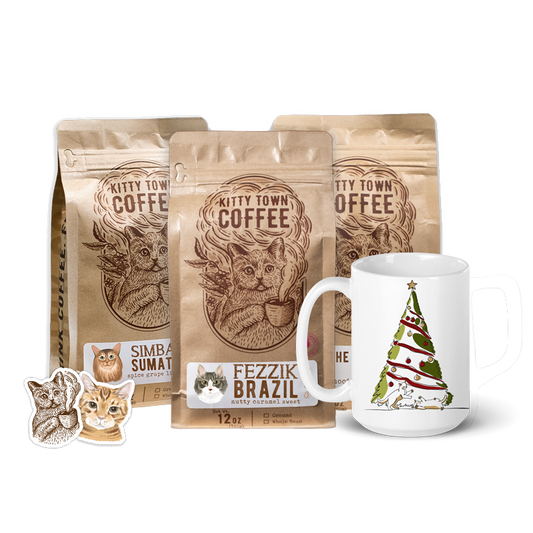 A picture of three bags of Kitty Town Coffee, a Christmas Mug, and two Kitty Town stickers