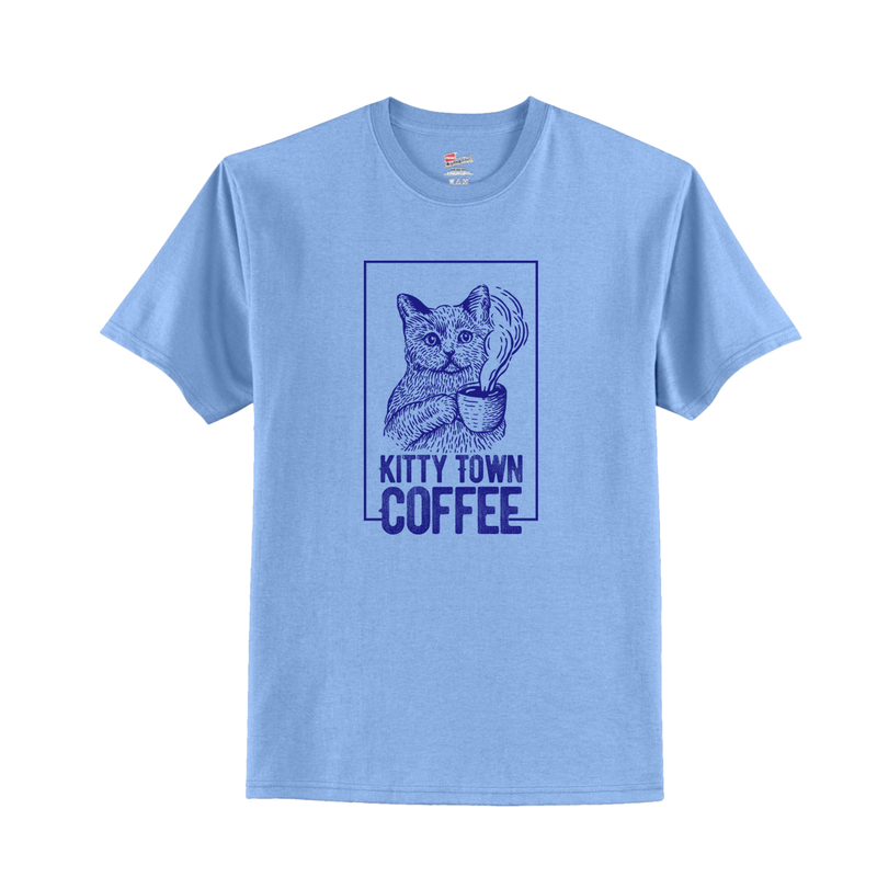 A light blue t-shirt with 'Kitty Town Coffee' text and a graphic of a cat in a square frame on the front.