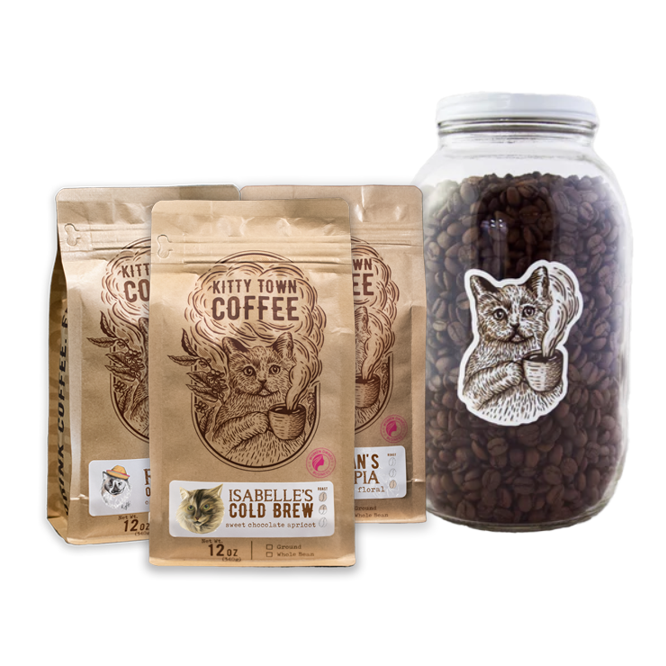 A collection of coffee-related items including three bags of coffee beans labeled 'Kitty Town Coffee' with different names, and a large 64oz glass jar with a metal lid, containing coffee beans and featuring a cat graphic.