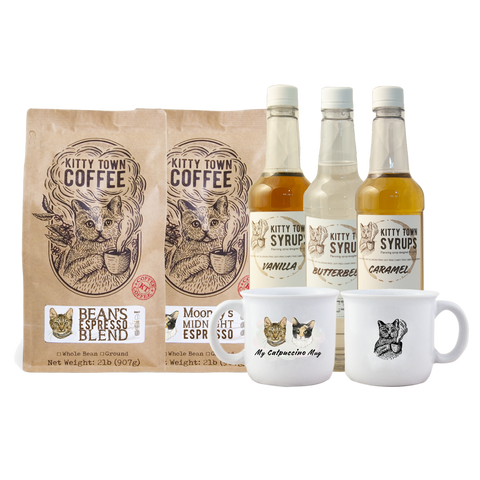 A collection of coffee and syrup bottles, two mugs, and bags of coffee beans with branding labels.